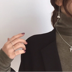 Detail view of minimalist silver layered necklace and woven rings worn with a blazer