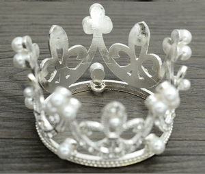 Close-up of a round silver crown with pearls on a dark wooden surface for weddings