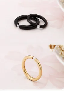 Detail of minimalist black and gold rings featuring tension-set round zircon stones
