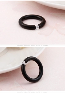 Detail of a thick black resin ring band featuring a tension-set sparkling round zircon