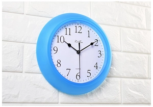 Close-up of a 22cm blue wall clock with black 3D numbers on a white textured background