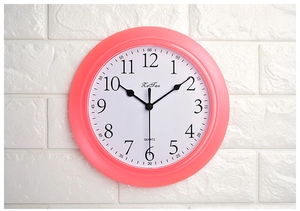Close-up of pink quartz wall clock with bold black Arabic numerals and white dial