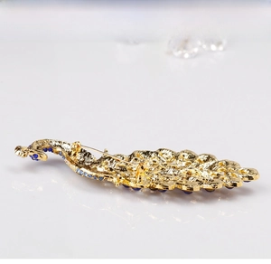 Detail view of the golden metal peacock brooch back showing the secure pin clasp design