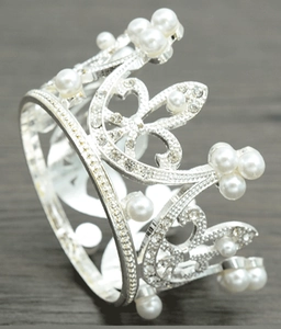Close-up of silver bridal crown with white pearls and sparkling diamonds on wood