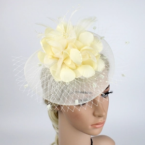 Detail of cream bridal fascinator hat with mesh net, mesh petals and feather accents
