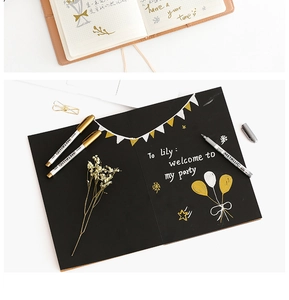 Metallic gold and silver markers writing on black paper for DIY scrapbooking