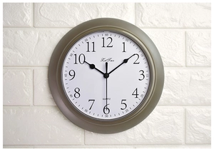 Detail of silent quartz wall clock showing precise 3D numerals and white dial on brick wall