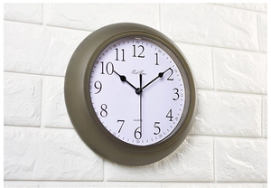 Side view of silent wall clock with bold 3D numerals on white brick wall background