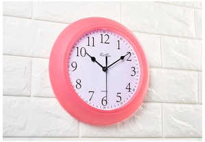 Close-up of pink silent wall clock with bold black Arabic numerals on white dial face