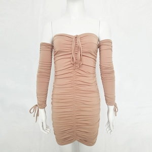 Détail d'une robe tube plissée nude avec manches longues détachées et détails de lacets