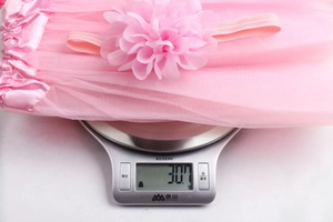 Pink chiffon tutu skirt and floral headband on a scale weighing 30.7 grams