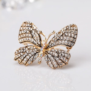 Elegant gold butterfly brooch with shimmering white and colored crystals on white background