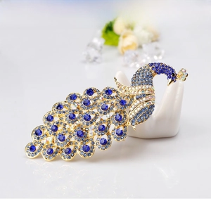 Macro detail of royal blue crystal peacock brooch set on a white hand display stand
