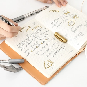 Metallic gold and silver craft pens writing on a planner for DIY greeting cards