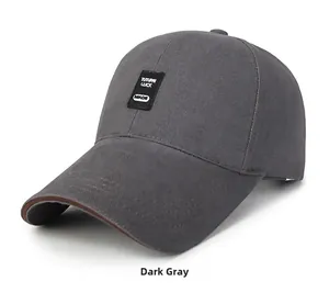 Detail of dark gray cotton baseball cap featuring black embroidered patch and brown brim piping