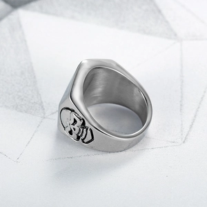 Detail of silver skull ring showing thick stainless steel band and punk design texture