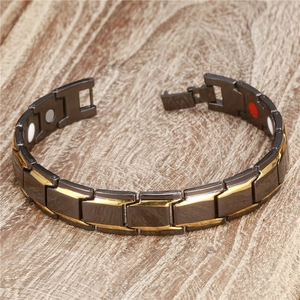 Detail view of magnetic health bracelet showing black and gold links on wood surface