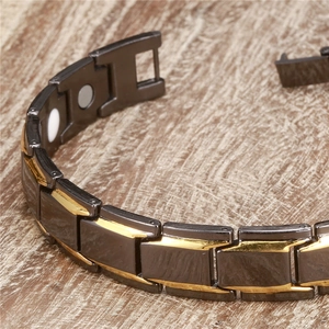 Macro shot of black and gold magnetic therapy bracelet links with clasp on wood