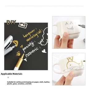 Detailed view of gold and silver metallic markers writing on paper and ceramic surfaces