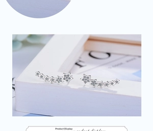 Detail of star-shaped earrings with sparkling cubic zirconia on a white display stand