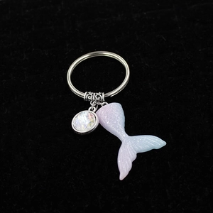 Detail of gradient mermaid tail keychain with a colorful charm and silver ring