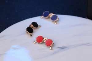Detailed view of red, black and blue enamel sunglasses brooches on white marble base