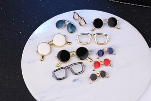 Macro shot of assorted colorful enamel sunglasses pins on a white marble tray