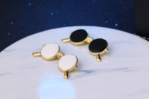 Detail shot of sunglasses cufflinks with gold frames and black and white enamel finish