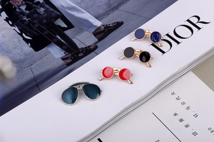 Detail showing vintage sunglasses enamel brooches in multiple colors on fashion magazine