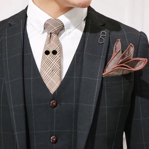 Close-up of brown plaid tie and pocket square with gold sunglasses brooch accessory