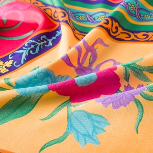 Macro view of floral pattern and twill texture on a premium orange silk satin scarf