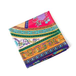 Close-up of folded silk scarf with vintage floral patterns in vibrant red and green colors