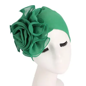 Detail of emerald green turban hat with a large layered mesh rose flower on the side