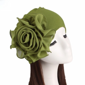 Detail of elegant green turban hat with a large chiffon floral accent on white model head