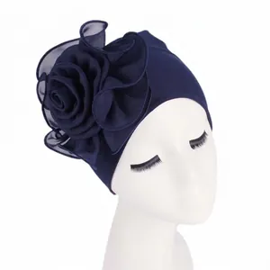 Detail of elegant navy blue turban featuring a large side-layered floral decoration