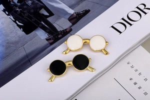 Detail of vintage round sunglasses brooches in black and white enamel on a fashion magazine