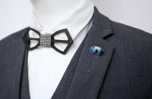 Close-up of a blue enamel sunglasses lapel pin on a professional suit jacket