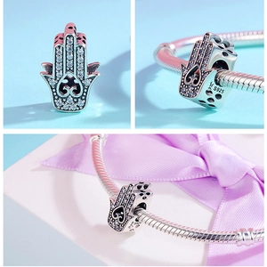 Macro detail of S925 silver Hamsa hand bead with crystals and heart pattern engraving
