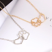 Detail of gold and silver heart pendants with hollow dog paw prints on cross chains