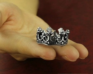 Close-up of vintage silver crown ring in stainless steel shown on a person finger