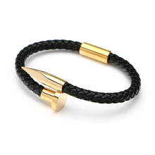 Detail of men's black braided leather bracelet with golden nail clasp and polished finish
