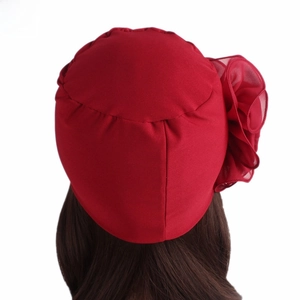 Rear view of red turban hat with large chiffon floral side detail on white background