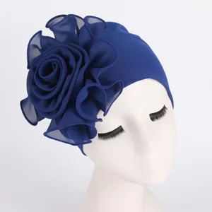 Detail of dark blue turban hat featuring large layered chiffon flower on stretch fabric