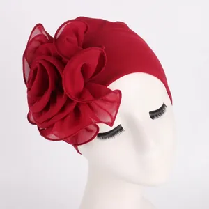 Detail of elegant dark red turban with a large side chiffon flower on a model head