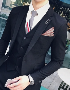 Detailed view of enamel sunglasses brooch on a formal black suit with a striped tie