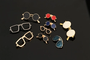 Macro shot of assorted colorful enamel sunglasses brooches in gold and silver metal frames