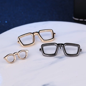Set of three fashion sunglasses brooches in gold and gunmetal on white marble