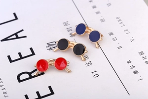 Detailed view of three enamel sunglasses brooches in red, black and blue colors