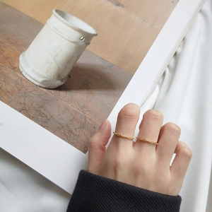 Detail of two ultra-thin 18k gold plated silver rings with twisted rope texture on hand