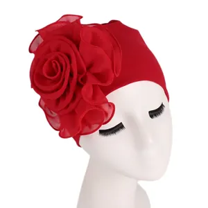 Detail of elegant red turban hat featuring a large layered chiffon side flower decoration